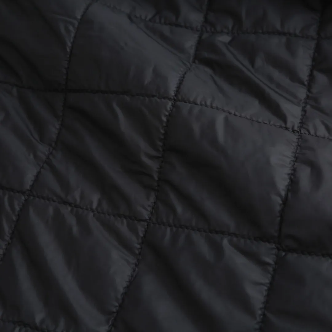 P650 Ralph Lauren pony embroidered light cotton jacket. The fabric is made of high-density nylon taffeta fabric, which combines pragmatism and classic texture. The density is about 210T-300T, the surface is smooth and slightly matte, it has excellent windproof and waterproof properties (with DWR water-repellent treatment), it has strong wrinkle resistance and is easy to care for, which is in line with the positioning of American casual "durable and practical". Classic dark black, using vat dyeing process (dye penetrates into the fiber), the color fastness reaches ISO level 4 or above, preventing fading or color transfer after washing. The lining is made of light cotton-polyester blended fabric (65% Polyester + 35% Cotton) to reduce the friction between the fabric and the inner clothing and improve the smoothness of wearing; the blended material has both breathability and durability to avoid the stuffy feeling of pure nylon lining. The style is a loose fit of the classic Coach Jacket, with slightly dropped shoulder lines (shoulder width is 1-2cm wider than the standard fit). The length reaches the hips, and the sleeves are slightly tapered straight sleeves, taking into account both freedom of movement and casual style. The Polo horse logo on the left chest is flat satin stitch embroidery (satin embroidery). Embroidery thread: 100% polyester high color fastness embroidery thread (the color number is consistent with the brand’s standard red color card). The stitch density is 12-15 stitches/cm. The outline of the horse logo is clear, and the details of the rider and horse are burr-free. The embroidery is positioned accurately through the template (12cm from the bottom of the neckline and 8cm from the placket) to ensure left-right symmetry and centering. The seams of the body are made of double-needle flat seams (needle pitch 3cm/10 needles), the stitches are flat and straight, the stitching color is dark black (the same color as the fabric), and the stitch width is 0.5cm, which enhances firmness while forming simple decorative lines. The front placket is spliced ​​with the body. The placket is made of double-layer folding + flat seam splicing. The thickness is about 0.3cm to ensure that the buttons are not easily deformed when fixed. The edges of the placket are cut with a hot knife to avoid burrs. The armholes where the sleeves and body are joined are made with round-head keyhole machine seams + flat seams. After splicing, the armholes have a natural curvature and no sense of tightness during movement. The height of the sleeves is about 8-10cm, which is in line with the loose characteristics of casual jackets. The main buttons are made of black urea resin buttons with a matte surface. The button holes are hand-made keyholes (6 strands of cotton thread, keyhole density of 8 stitches/mm), and the edges of the eyelets are smooth and without burrs. The first button on the neckline is a hidden button (diameter 12mm), which prevents the neckline from opening and improves the neatness of wearing. Size:S-M-L-XL